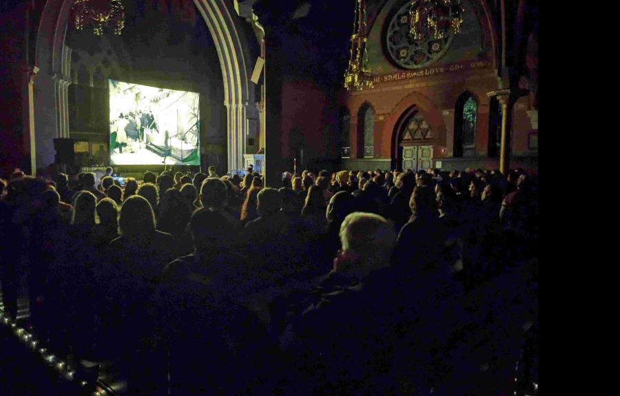 A group of people watching a movie inside a darken Gothic church.