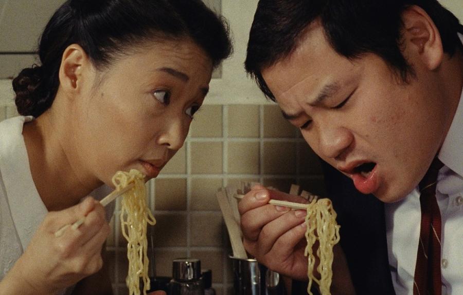 A man and a woman eating ramen noodles with chopsticks.