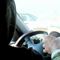 A close up shot of a woman behind a steering wheel wearing a black hijab