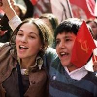 Three children in school uniforms cheering and waving flags.