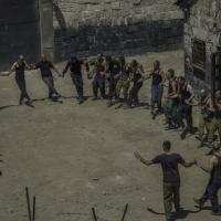 A group of man in a prison yard holding hands in a circle.