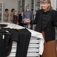 Four women standing together looking at a black tuxedo and laughing.