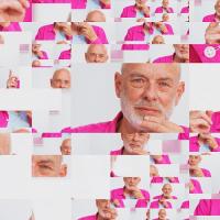 A pixeled image of a man with a white beard wearing a pink shirt.