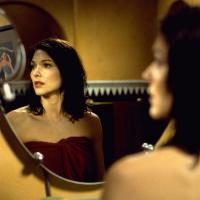 A woman with brown hair looking away from her reflection in the mirror.