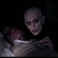 The vampire character Nosferatu leans over a sleeping victim.