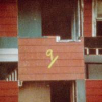 A red building exterior cut into squares with the number 9 written in yellow at center.