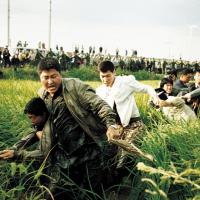 A group of distressed looking people running through a field.