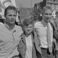 A black-and-white photograph of four students marching arm-in-arm at a protest.