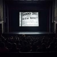 A group of people watching an old movie inside a darkened theatre.