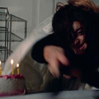 A blurry image of a terrified woman reaching for a birthday cake