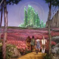 Scene from 'The Wizard of Oz' with Dorothy, the Scarecrow, Tin Man, and Cowardly Lion walking along the yellow brick road through red flowers toward the glowing green Emerald City