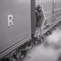 A well dressed woman clings to the side of a moving freight train.