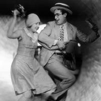 A joyous man and woman running arm-in-arm inside a tunnel.