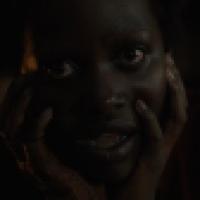 A person with wide eyes and slightly open mouth hold their hands on either side of their face against a dark background.