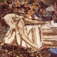 An artists recreation of a photograph using items from a landfill, depicting a person in a reclining position.