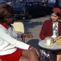 Two woman sitting at a sunny cafe table.