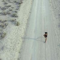 A boy running alone on a dusty desert road.