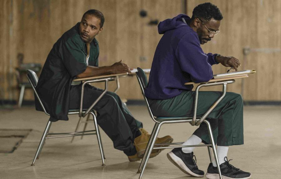 Two men sitting in metal desk chairs.