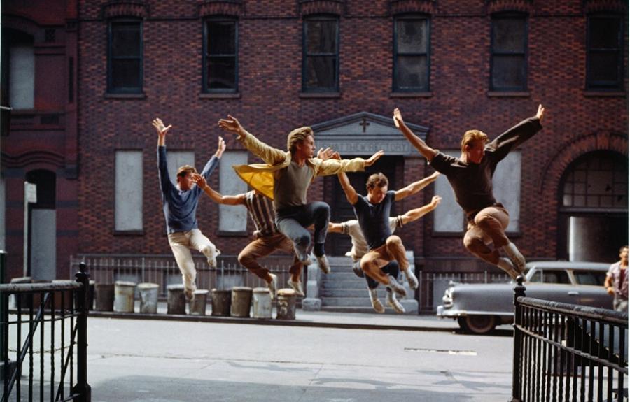 A group of dancing men suspended in mid-air on a city street.
