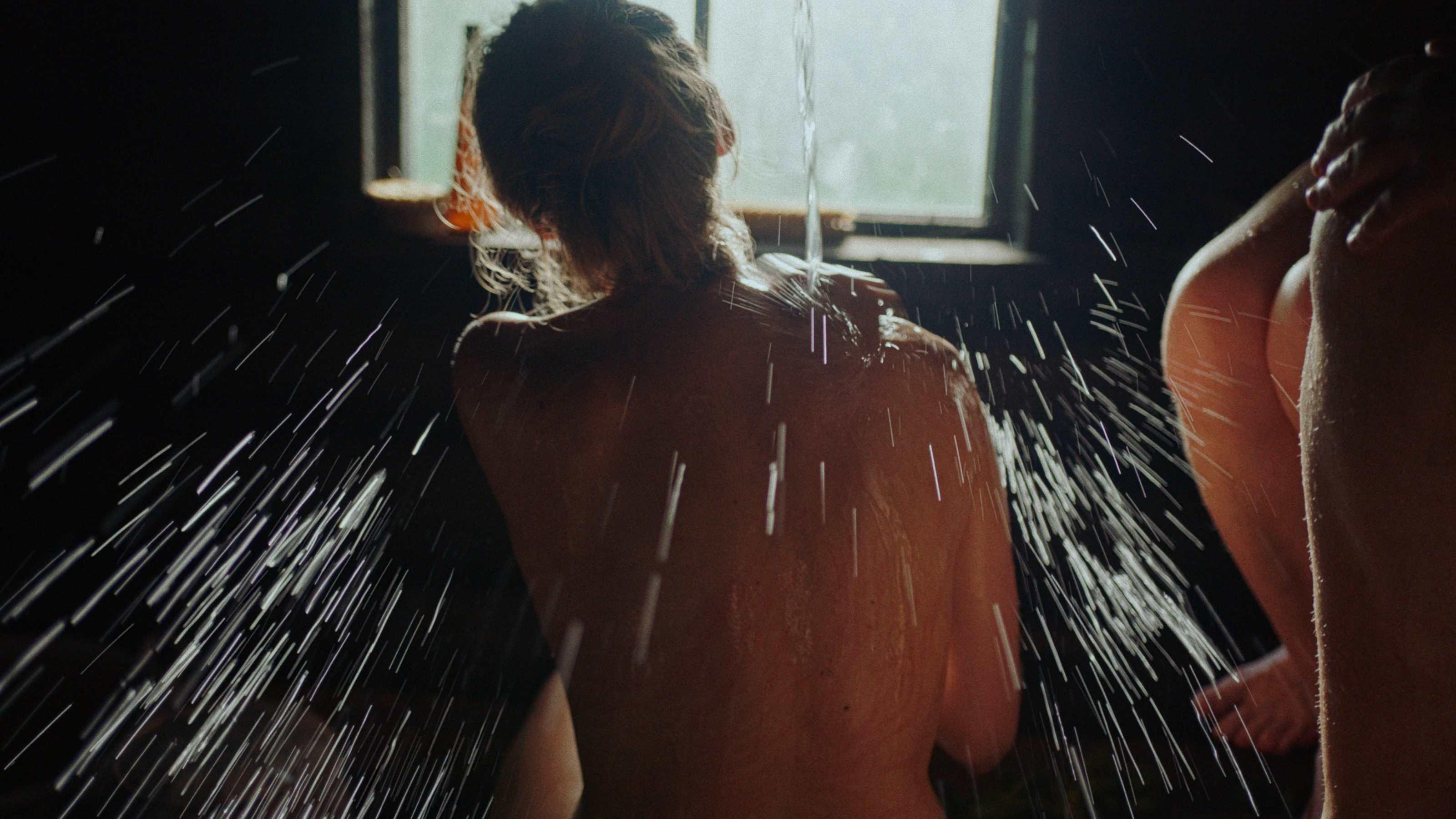 A women in a sauna splashes herself with water.