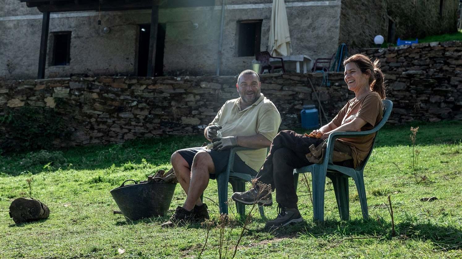 A couple sitting in lawn chairs on a sunny green lawn.