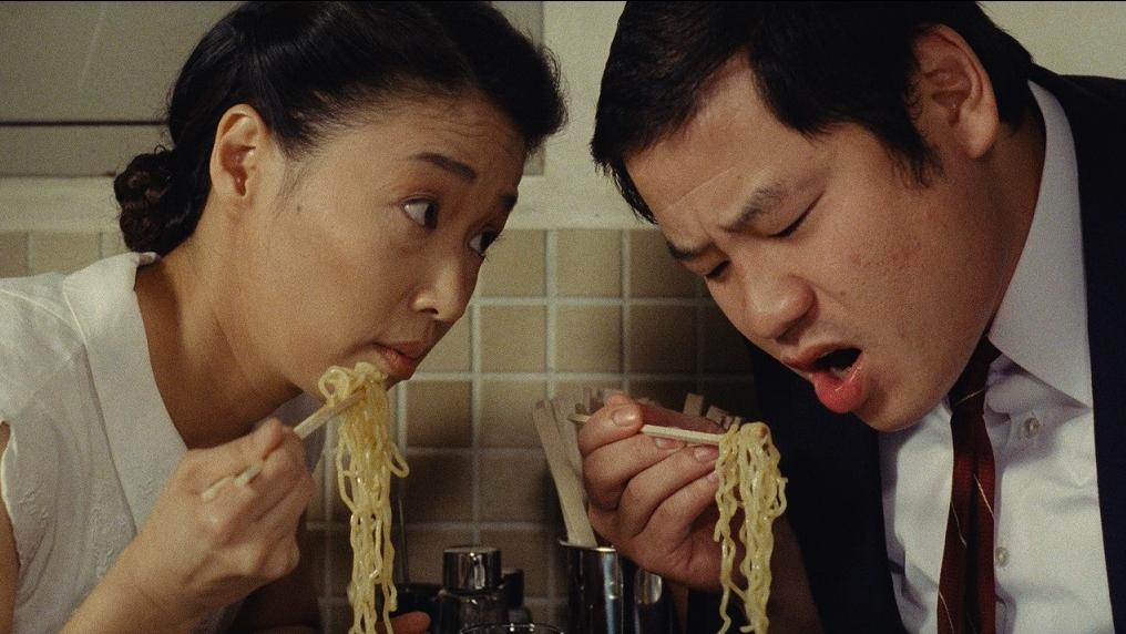 A man and a woman eating ramen noodles with chopsticks.