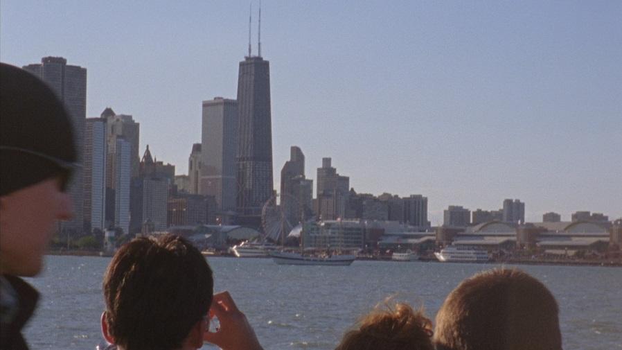 A group of people taking photos of a city skyline from a boat.