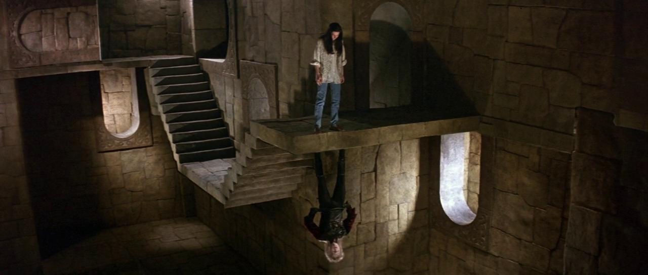 A scene with an architectural illusion where the laws of gravity appear to be defied. It features two individuals on different planes of a room that is constructed in such a way that one person seems to be standing normally on the floor, while the other a