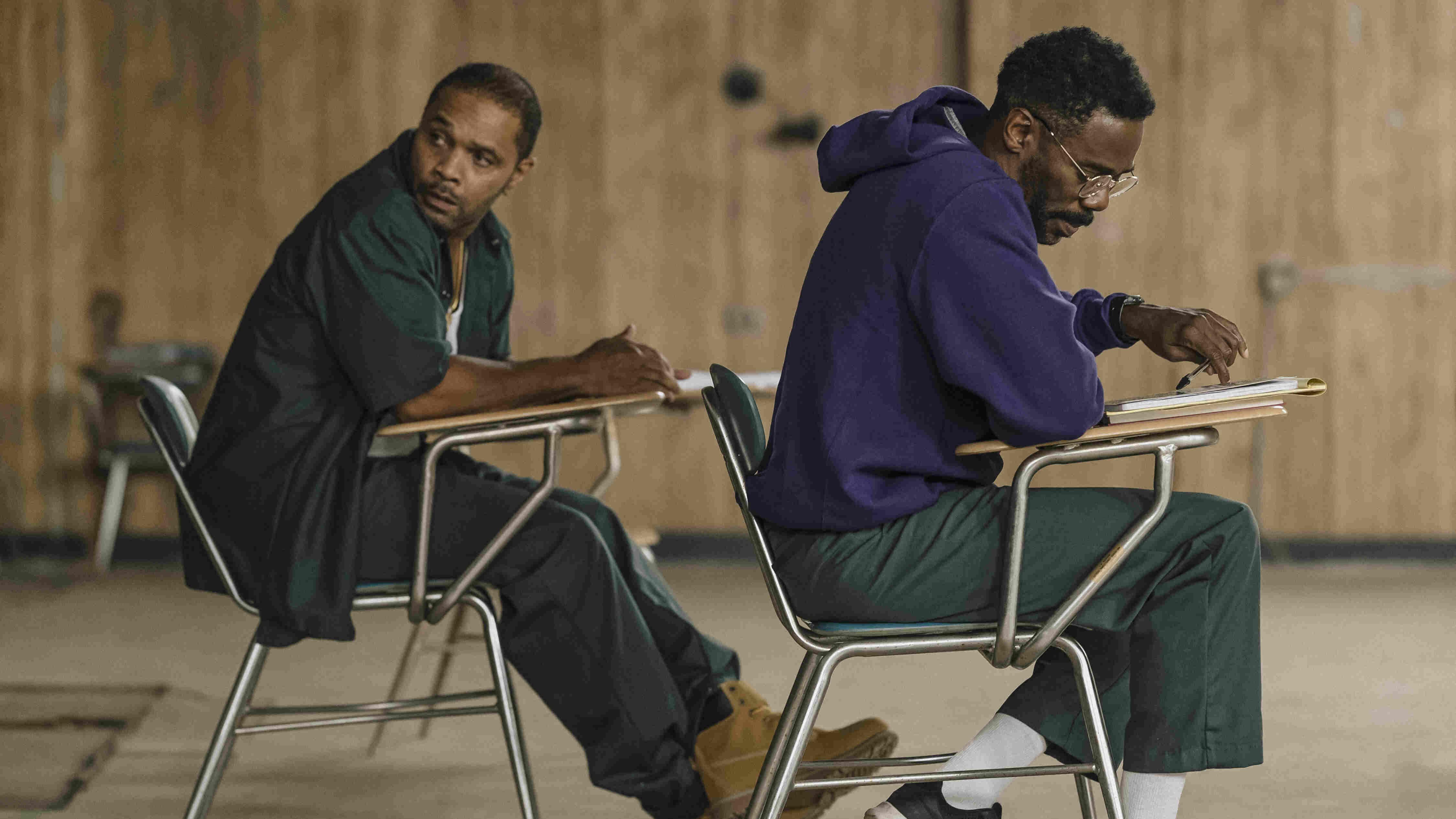 Two men sitting in metal desk chairs.