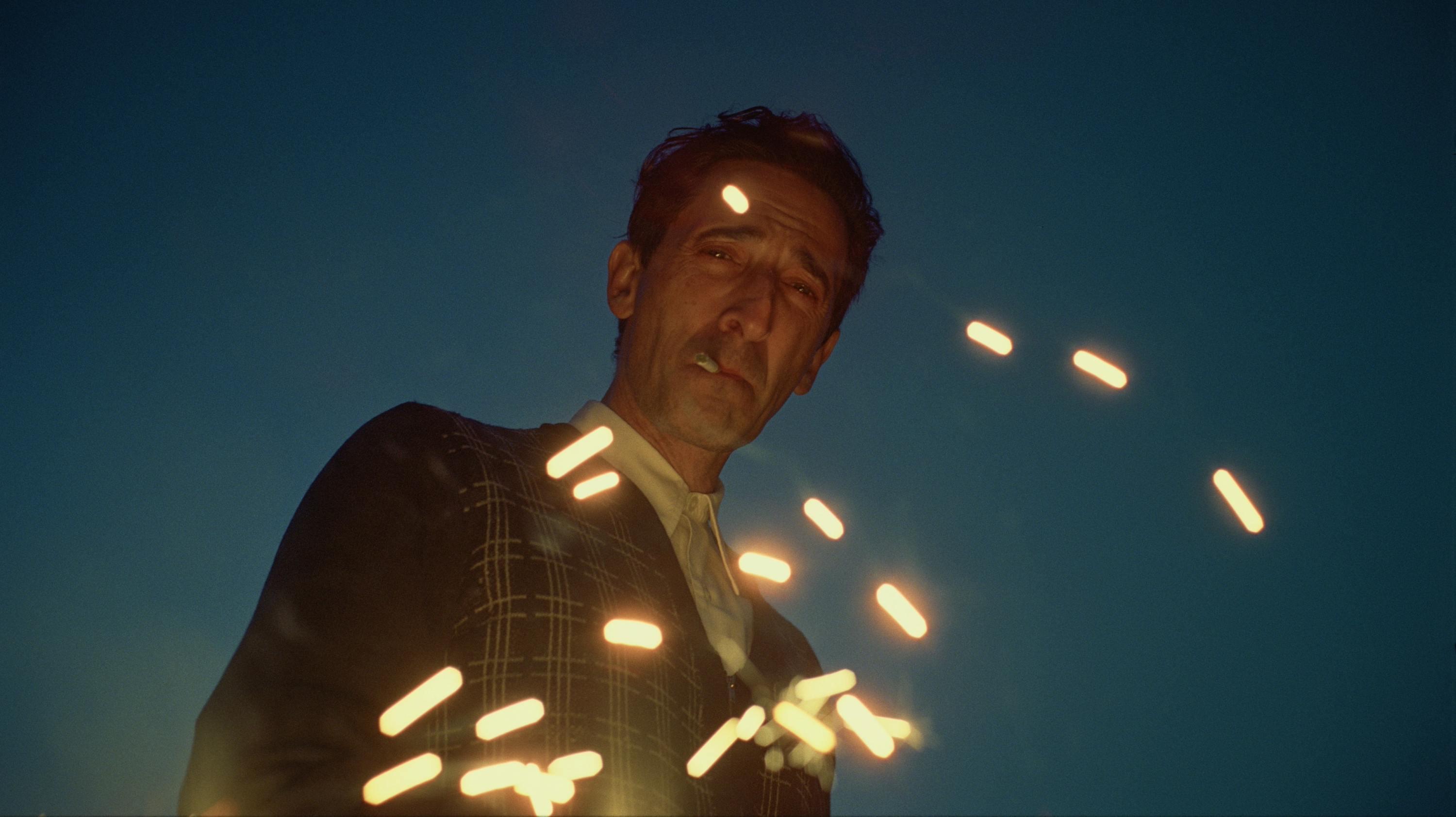 A man smoking a cigarette with sparks flying in front of his windswept face.