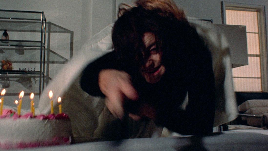 A blurry image of a terrified woman reaching for a birthday cake