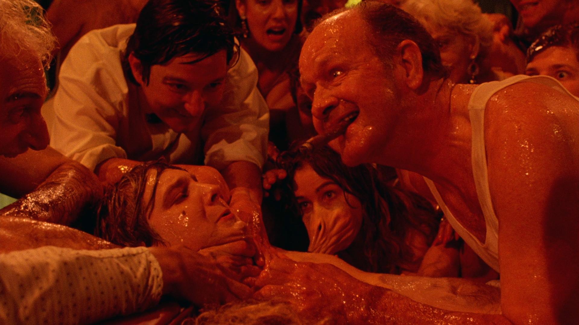 A group of people covered in a clear slime surround a person with their hands around the person's neck