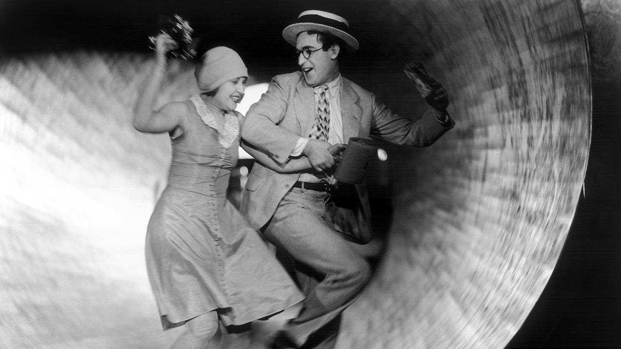 A joyous man and woman running arm-in-arm inside a tunnel.