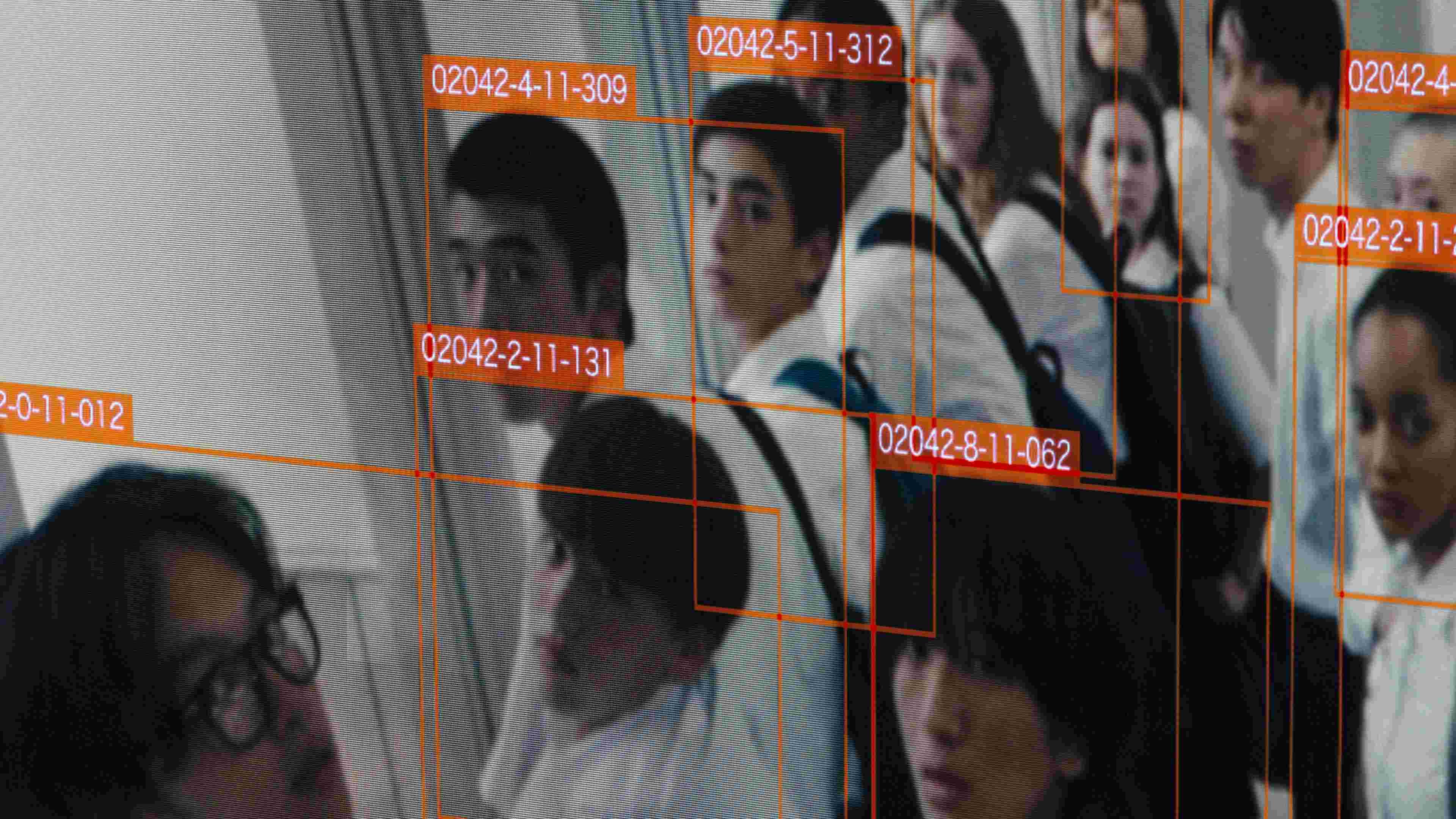 A surveillance photo of a group of high schoolers wearing white shirts each labeled with a red box with a number.