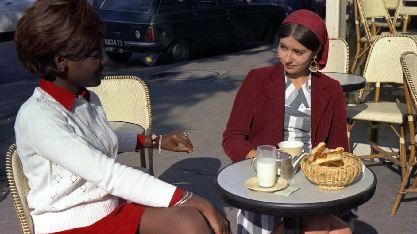 Two woman sitting at a sunny cafe table.