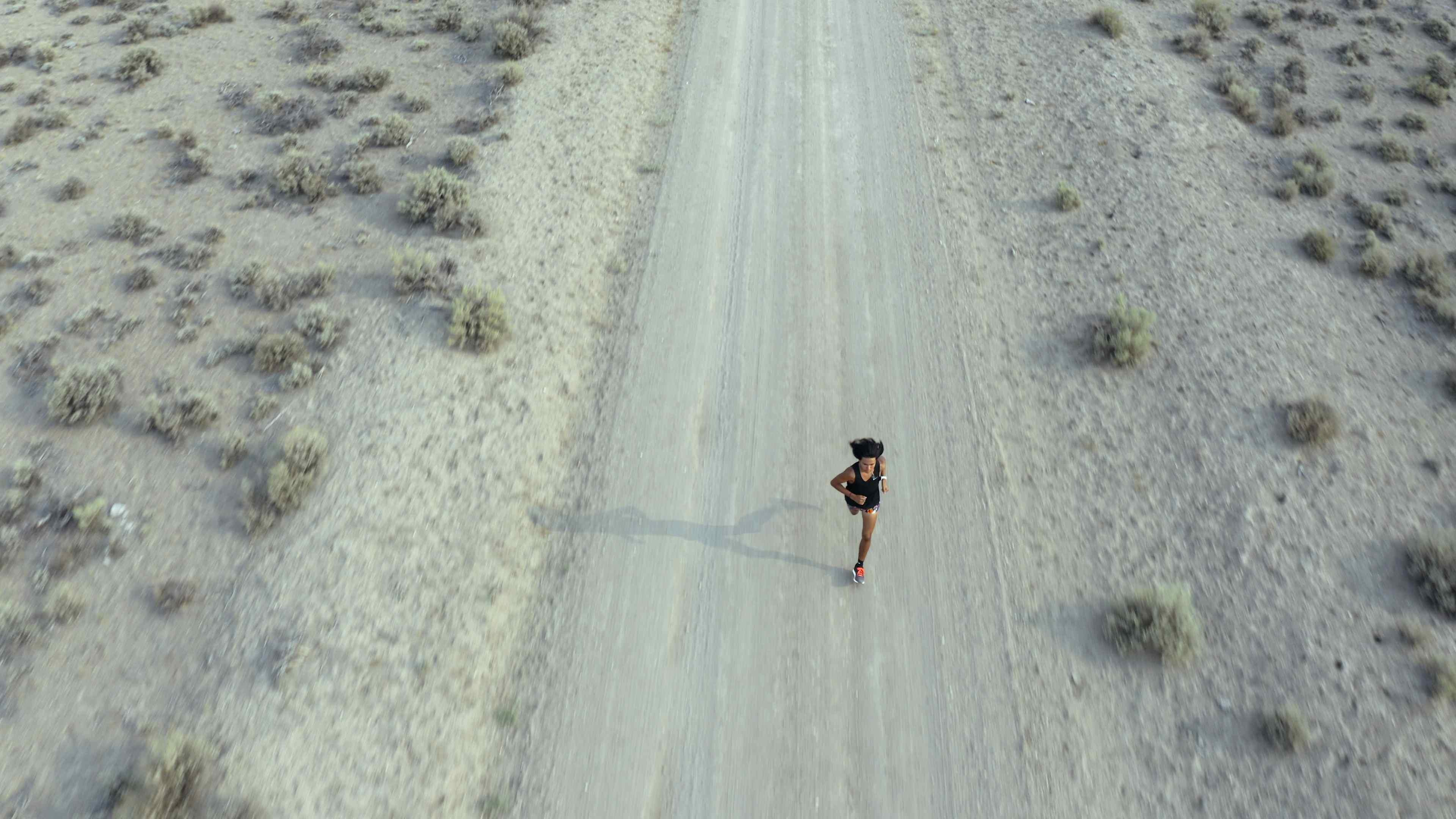 A boy running alone on a dusty desert road.